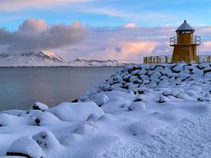 Reykjavík - Höfði Lighthouse. Lighthouse at sunrise overlooking a snow covered Faxaflói Bay