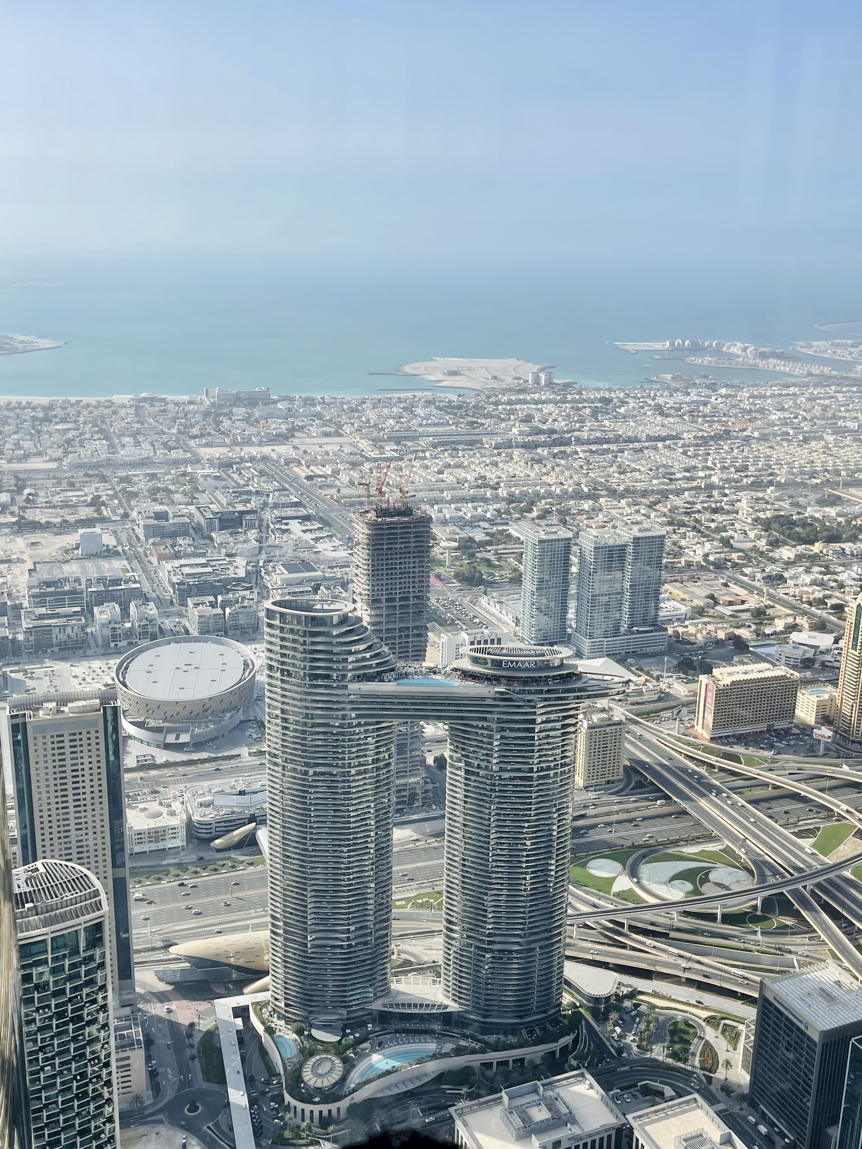 An aerial view of a city with a unique skyscraper connected by a bridge.