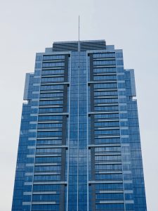 A prominent blue-glass high-rise building in downtown Portland, Oregon, featuring numerous windows and a modern architectural design