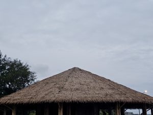Thatched hut blending with the coastal landscape under a cloudy evening sky at Chaliyam Beach, Kozhikode.