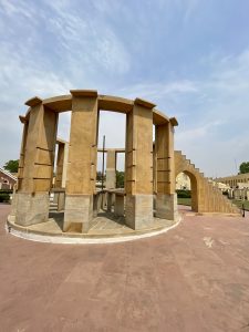 An architectural structure at Jantar Mantar, Jaipur, stands tall under a partly cloudy sky