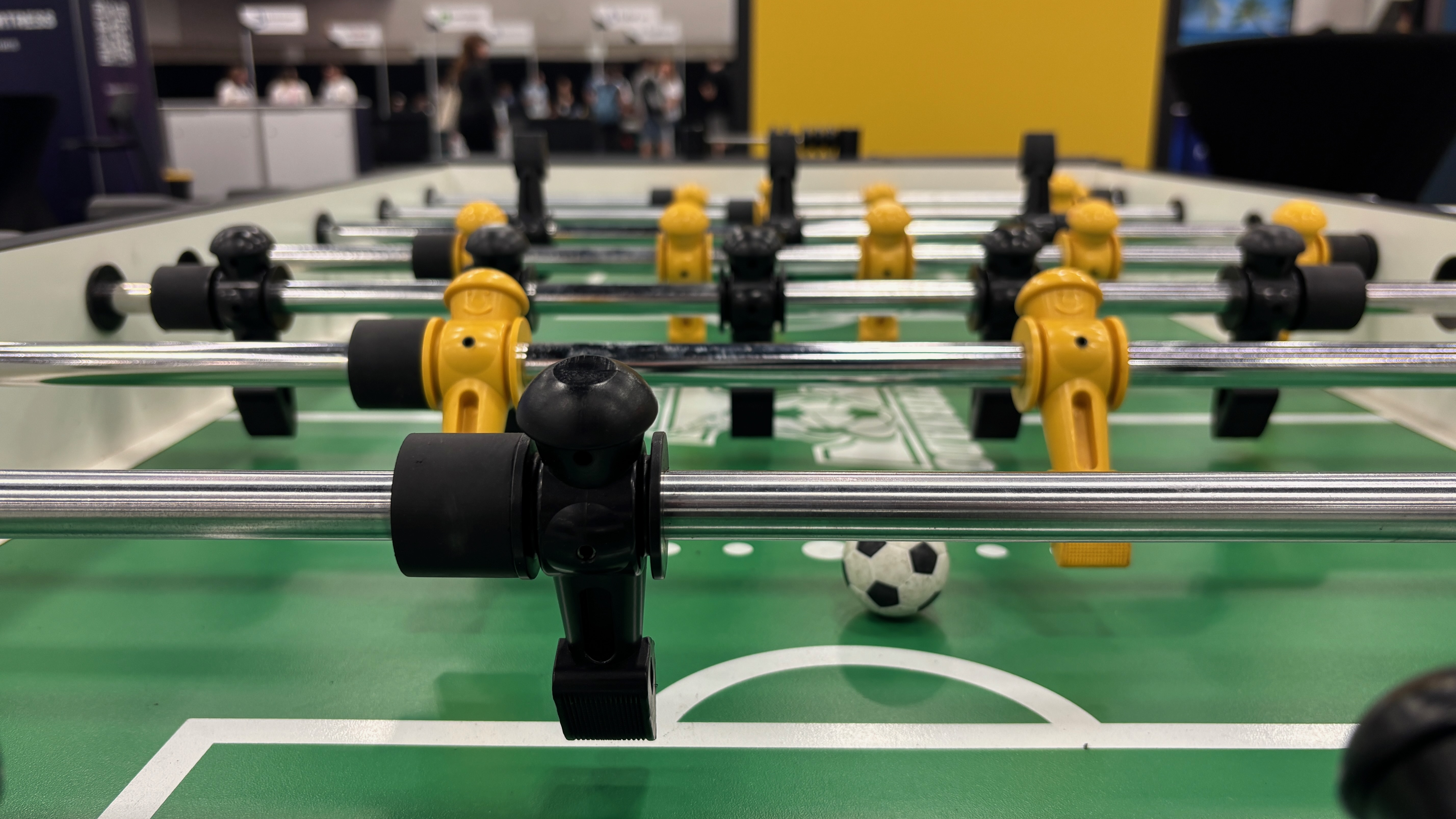 A foosball table, taken from the vantage point of the goalie. There's a ball in frame.