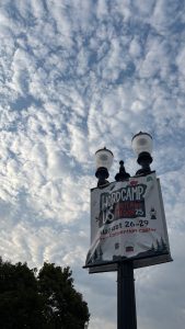 A lamp post with two lights at the top.  The view is from below, and much of the picture is sky with puffy clouds.