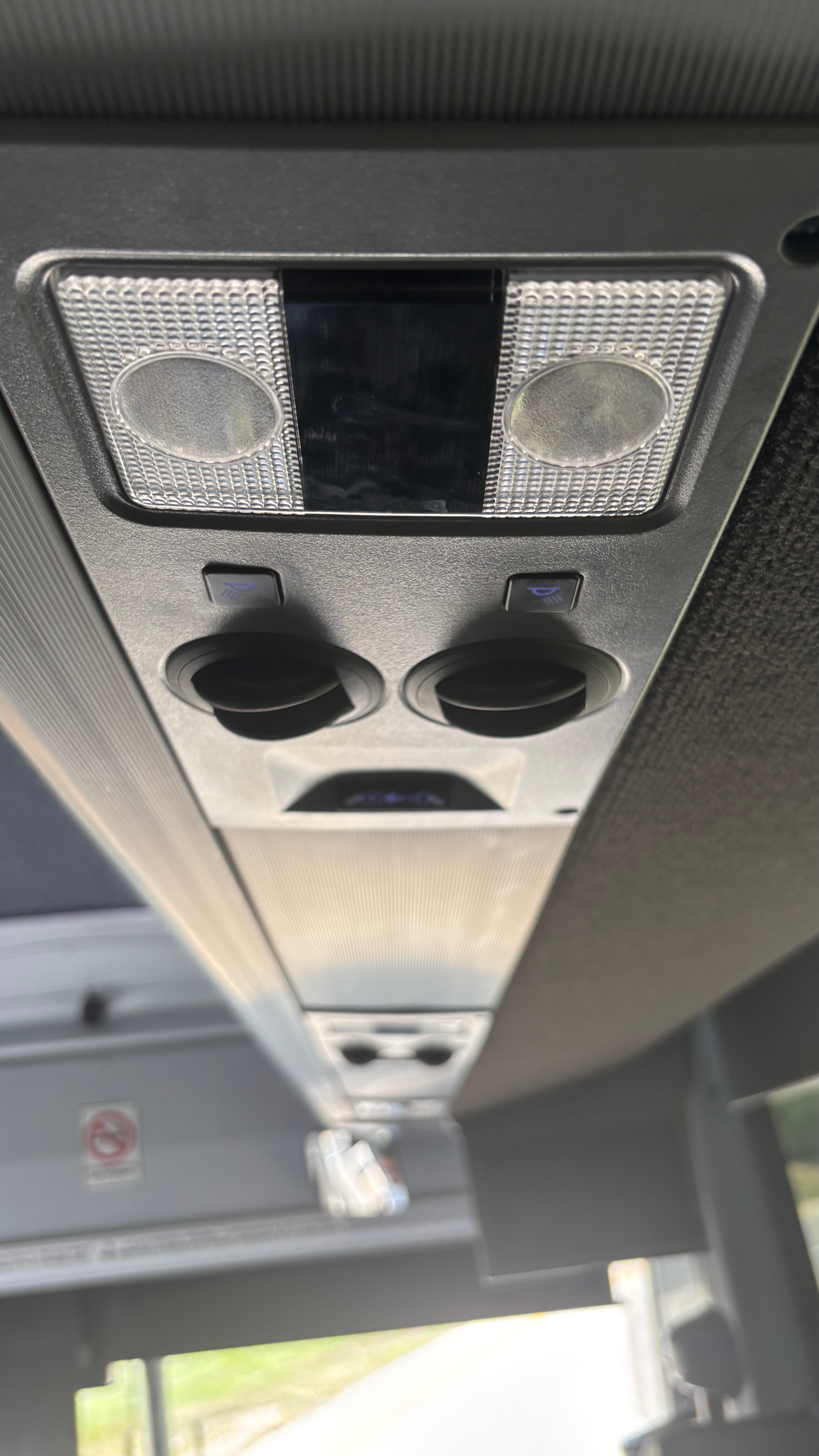 Lighting and air controls in a panel over a bus seat.