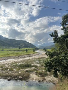 A serene landscape featuring a winding river bordered by lush greenery and fields.