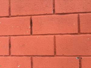 A close-up view of a textured red brick wall.