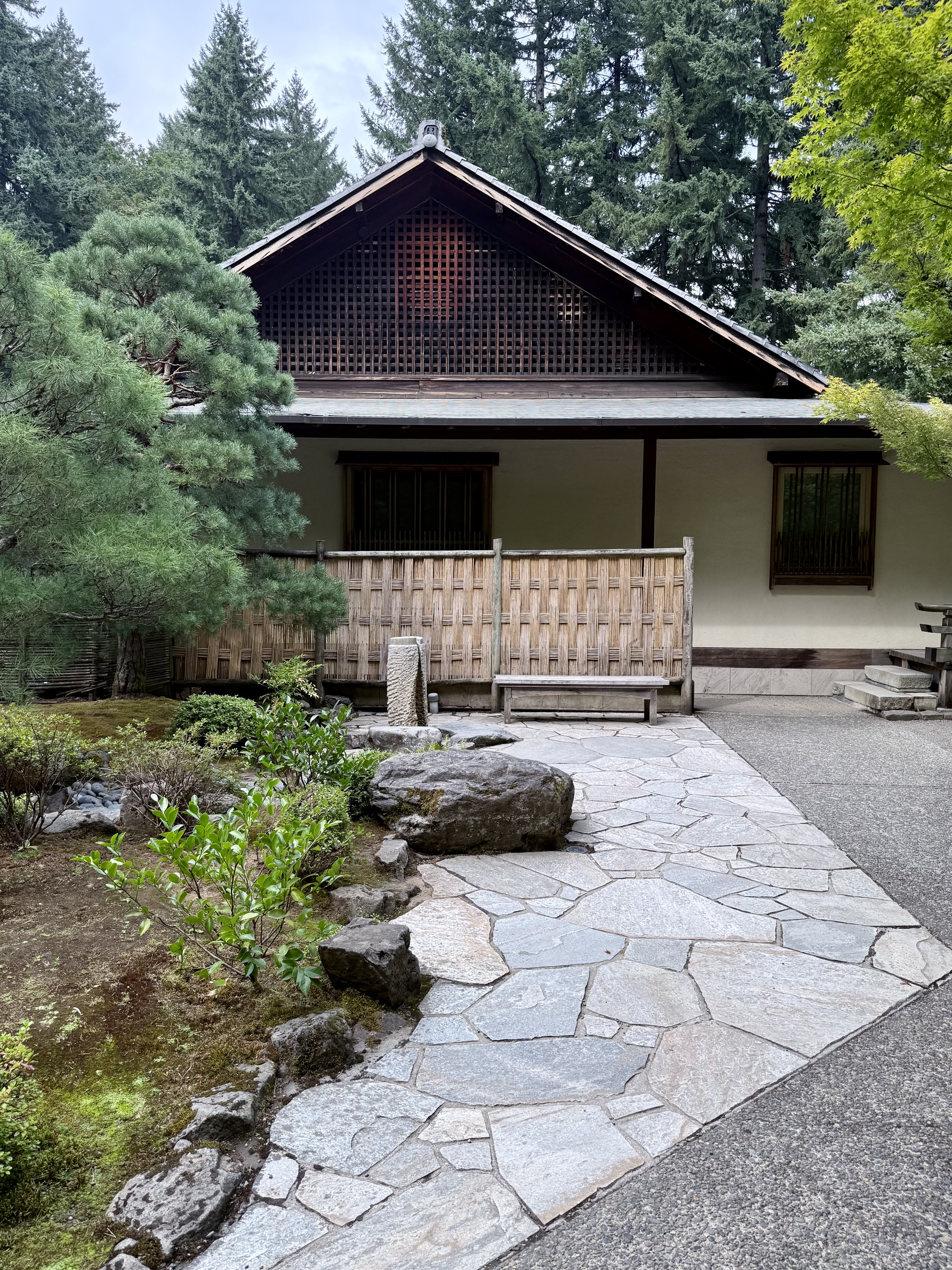 Traditional Japanese wooden house with bamboo fence, stone path, and natural garden. Photo taken at the Portland Japanese Garden, Oregon. 