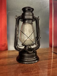 A vintage oil lantern is displayed on a wooden surface.
