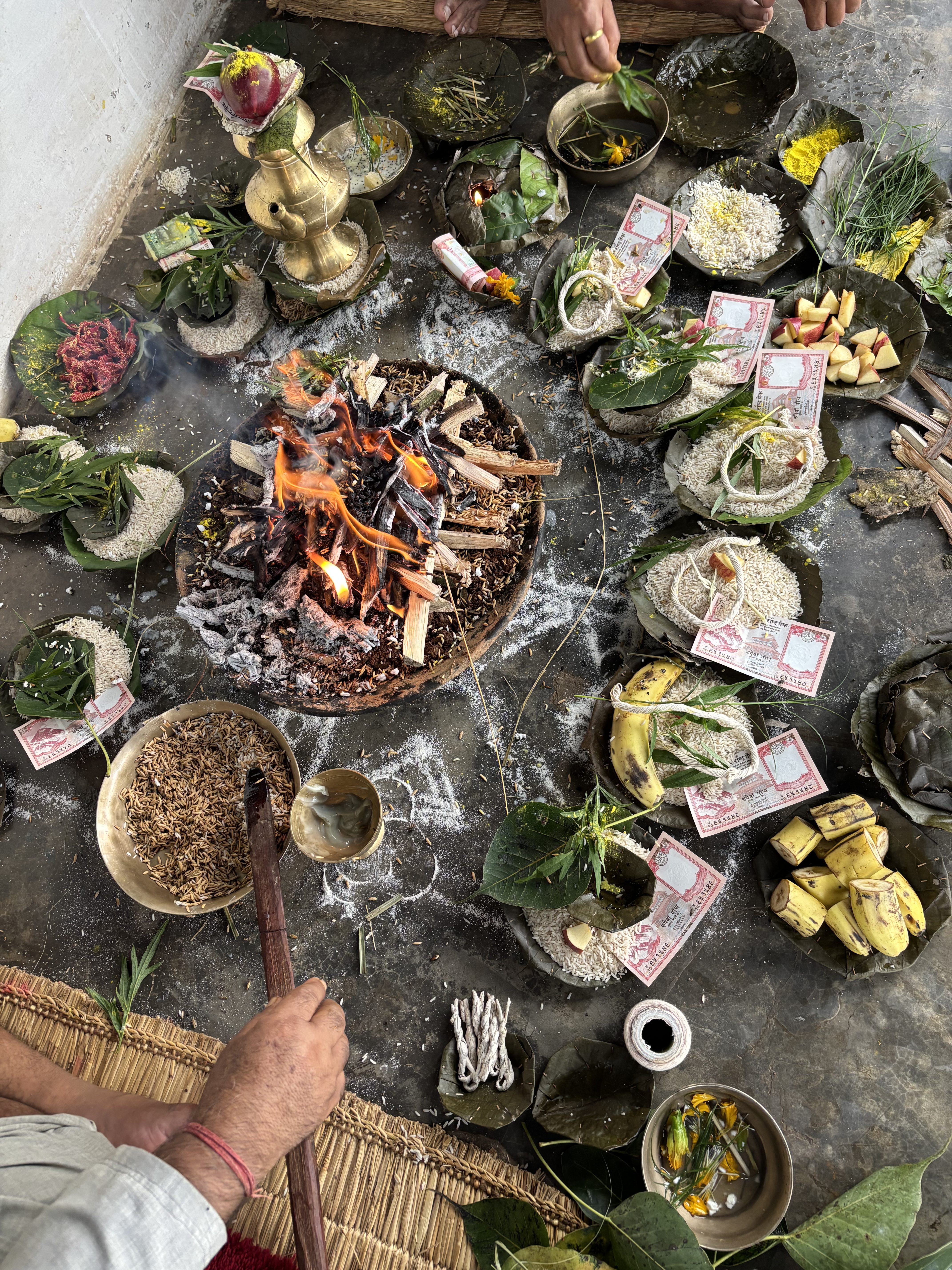 A ceremonial setup featuring a central fire surrounded by various offerings. 