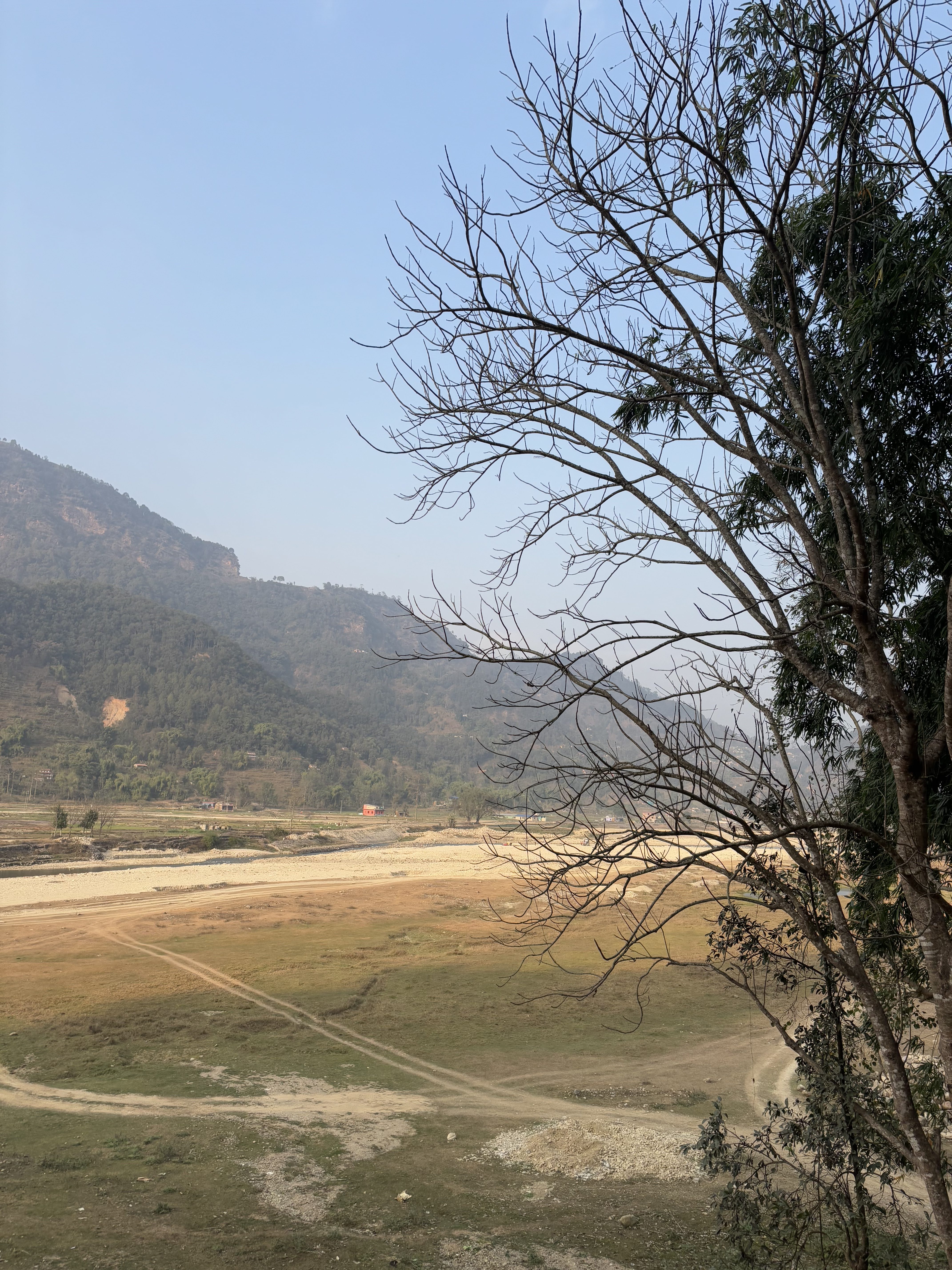 A panoramic view of a dry landscape featuring a meandering dirt path and a sparse, rocky terrain at the foreground.