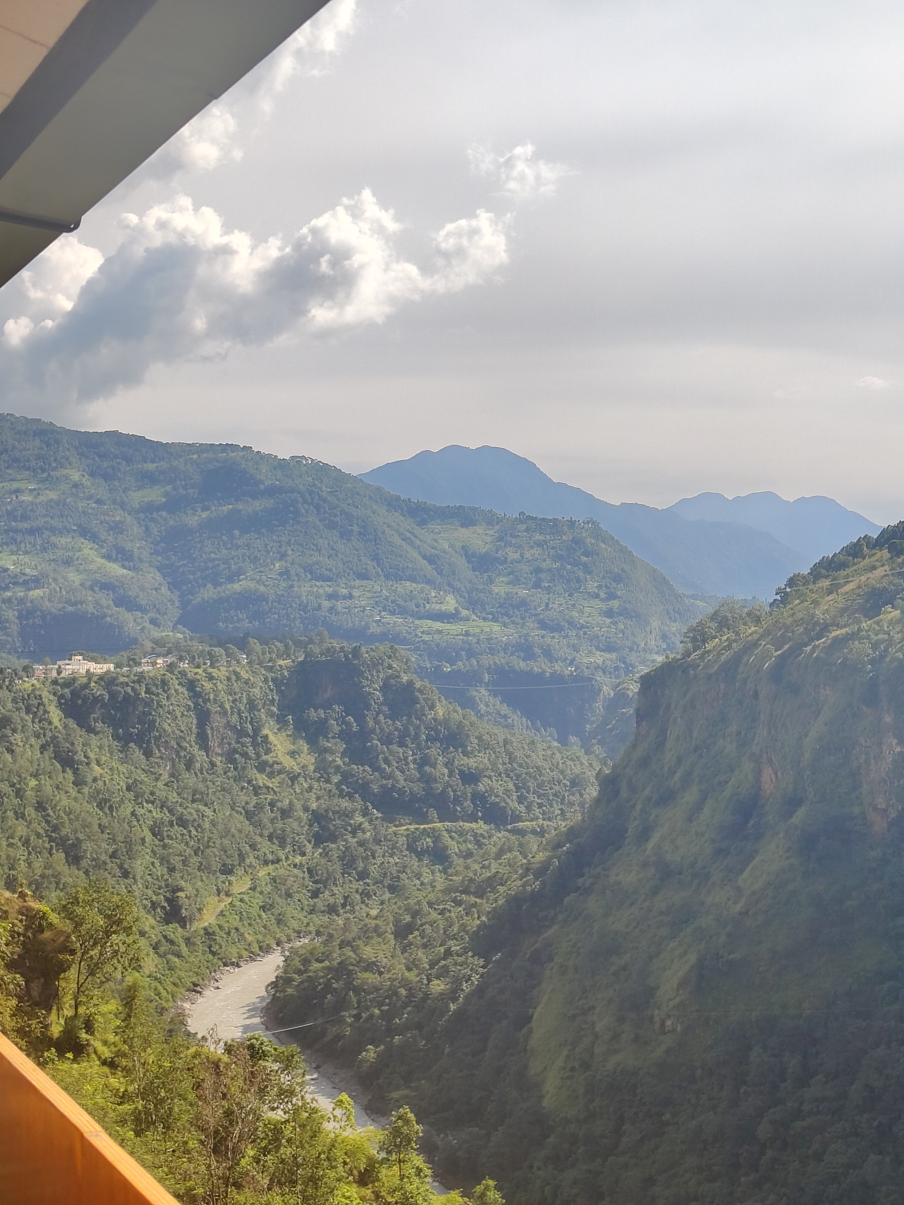 A scenic landscape featuring lush green mountains and a river flowing through a valley.