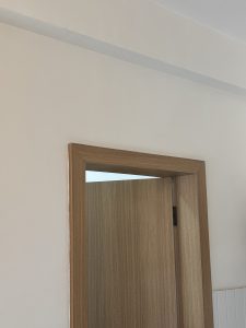A close-up view of a wooden door frame against a plain white wall.
