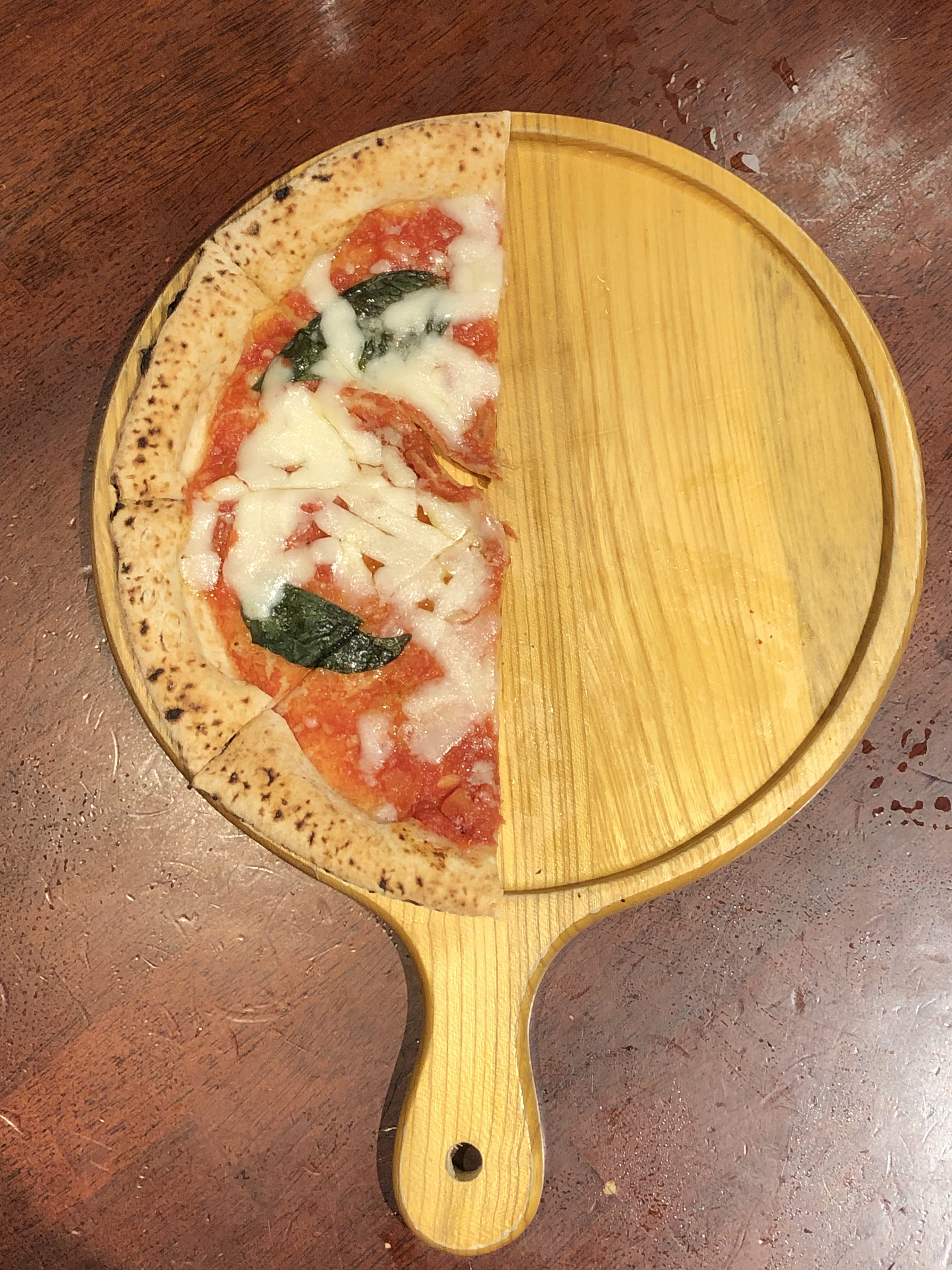 A half-eaten pizza on a wooden pizza peel.
