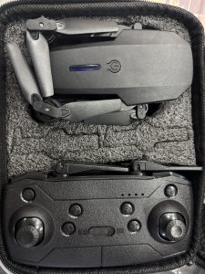 A compact black drone with foldable arms is placed inside a protective foam-lined case