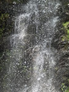 A close-up view of cascading water creating a misty effect as it flows over a rocky surface, with droplets sparkling in the ligh