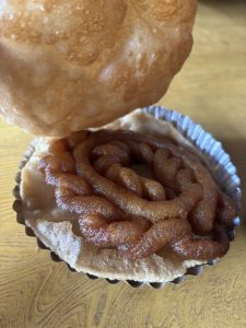 

Golden-brown puri with a syrupy spiral-shaped semolina sweet on a plate.