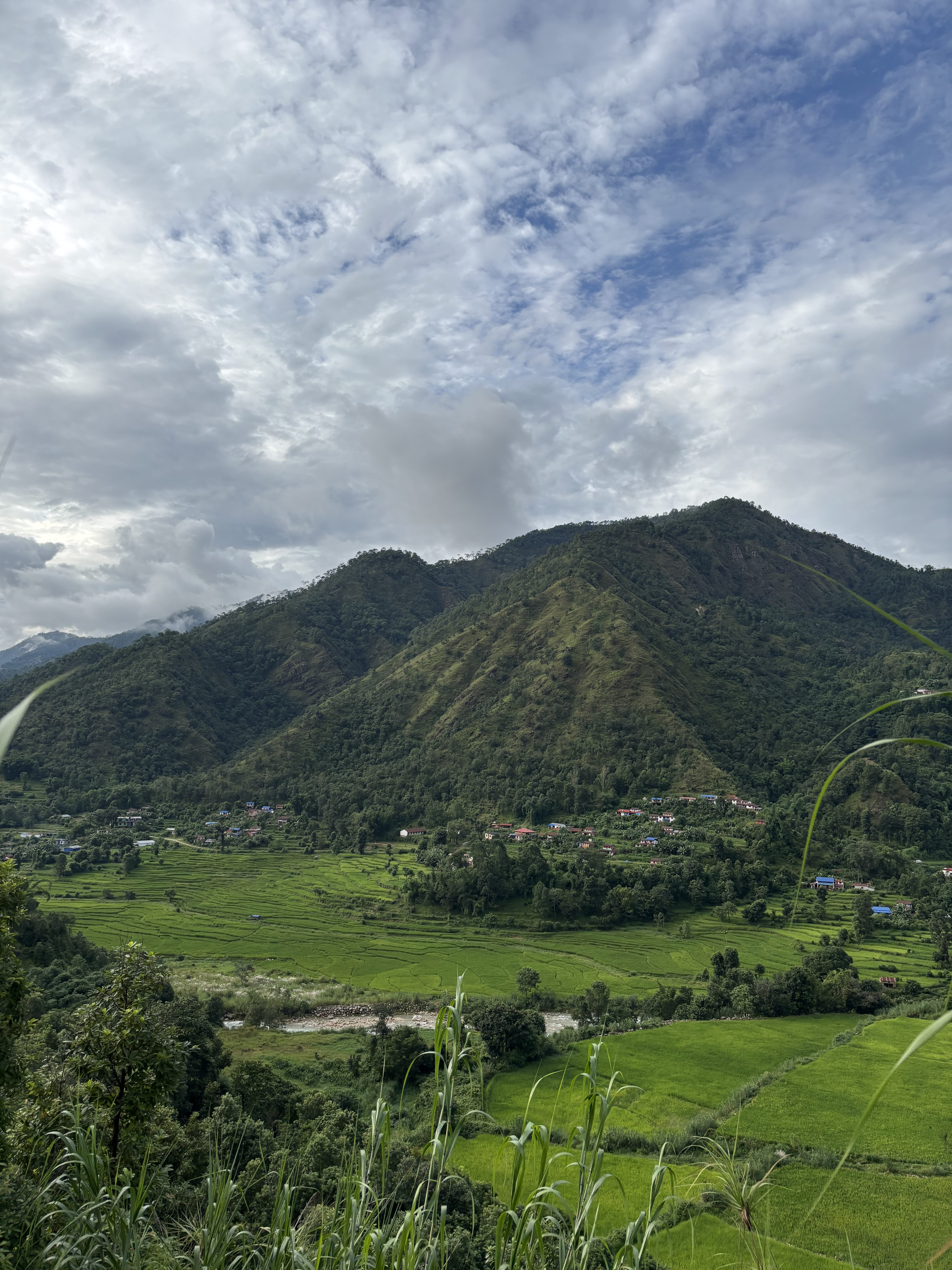 A scenic landscape featuring lush green hills and terraced fields with a river running through the valley.
