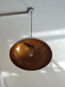A modern pendant light with a large, round amber shade hangs from the ceiling.