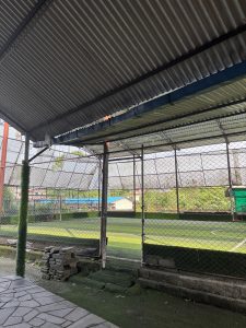The image shows the interior of a sports facility, specifically a fenced area that appears to be a small soccer fiel