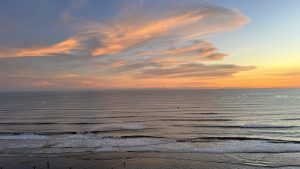 A serene beachfront view during sunset, featuring soft waves lapping against the shore. 