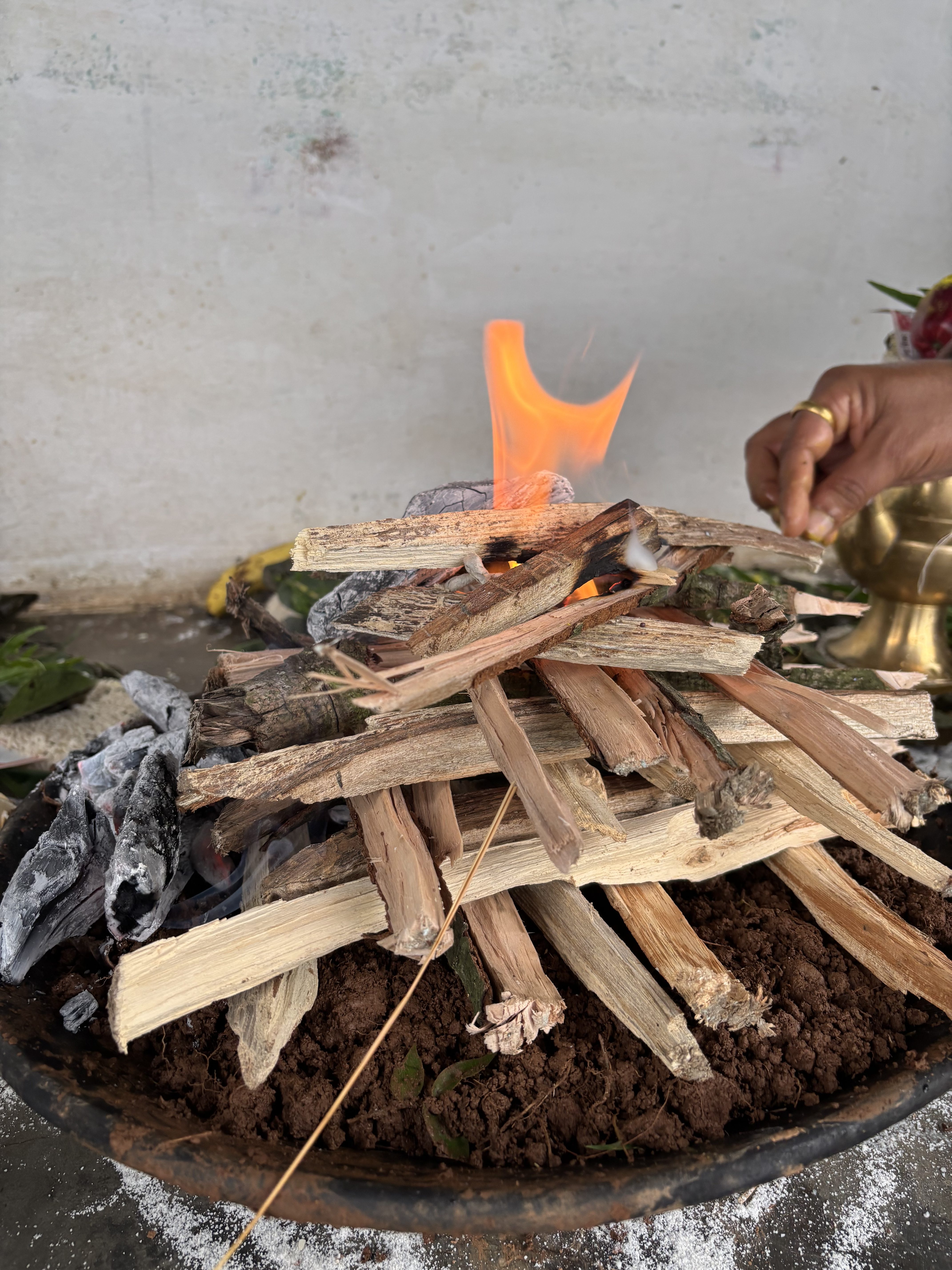 A small ceremonial fire pit is shown with a stack of wooden sticks arranged in a teepee shape, partially engulfed in flames.