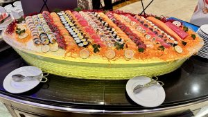 A large decorative platter filled with an assortment of sushi rolls and sashimi, featuring vibrant colors and various types of fish.
