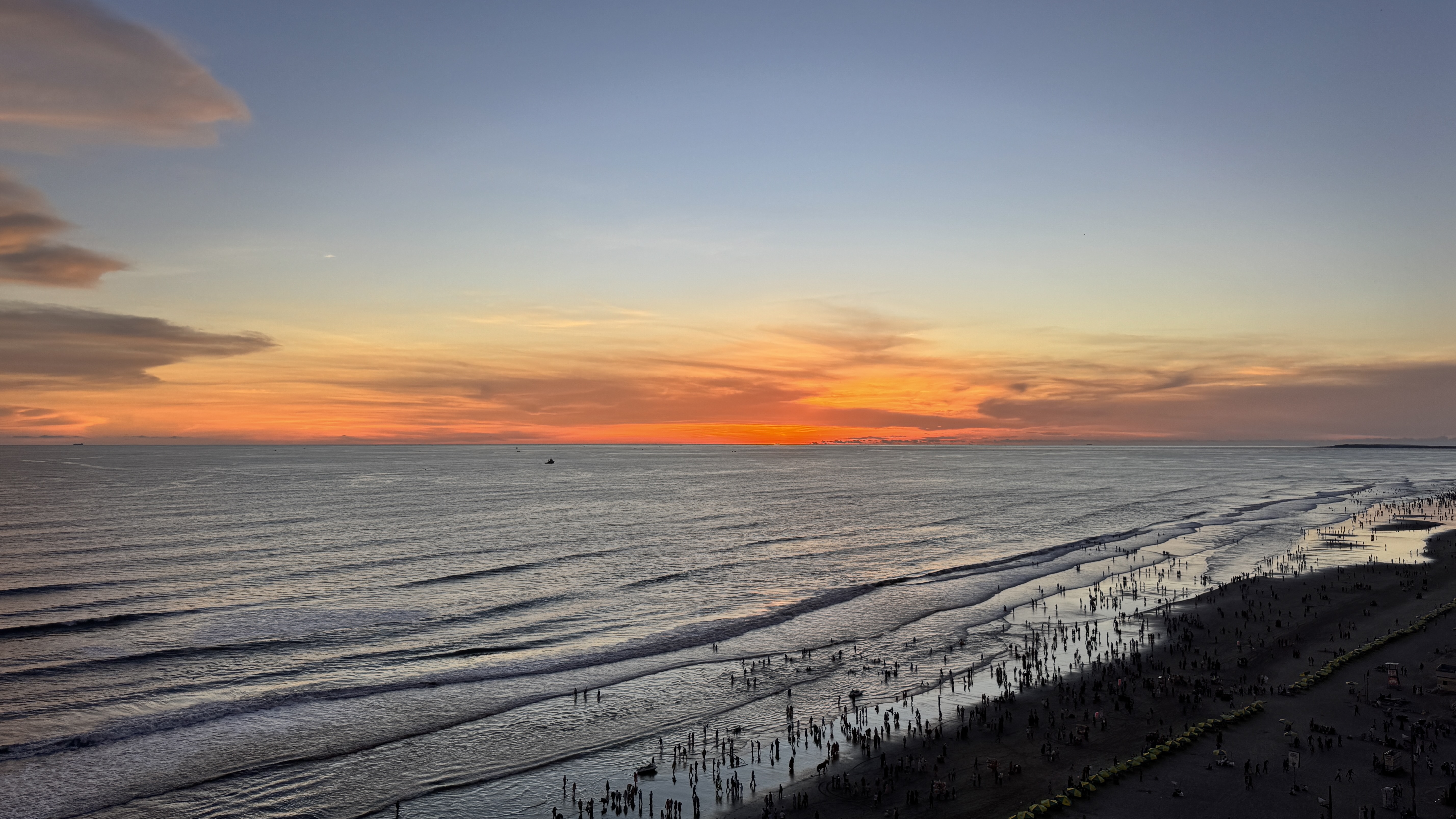 A serene beach scene at sunset, featuring gentle waves lapping against the shore.