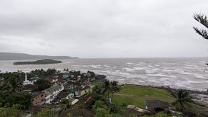 A coastal view showcasing a stormy sea with rolling waves under overcast skies.
