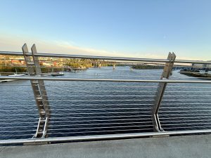 View from Tilikum Crossing Bridge, Portland, looking over the Willamette River and buildings on the opposite bank under a clear blue sky. 