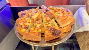 A silver platter holds several slices of pizza, arranged in a circular pattern. 