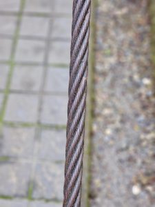 A close-up photo of a thick, twisted steel cable used as a support rope, clicked near a trail path close to Thusharagiri Falls, Kozhikode, Kerala. 