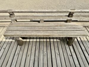 A simple wooden bench on a wooden deck overlooks the raked gravel of the Zen Garden. A quiet resting spot in Portland Japanese Garden. 