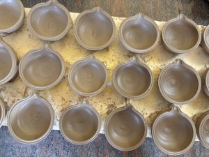 A close-up view of several unfinished clay ( Akhanda Deepa) bowls arranged in a grid pattern on a surface
