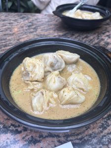 A bowl of dumplings submerged in a creamy sauce with specks of seasoning.