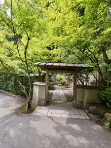 A simple Japanese-style wooden gate opens to a stone path, inviting visitors into Portland Japanese Garden.