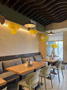 A cozy café interior featuring wooden tables with light green chairs. 