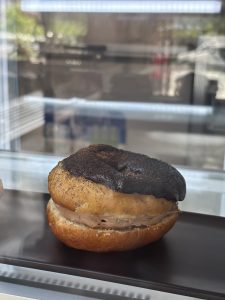 A close-up of a donut with a layer of creamy chocolate filling between the top and bottom halves.