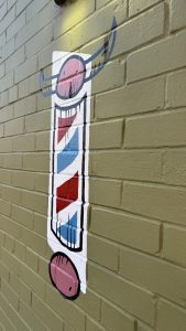 A barber's pole painted on a wall.  The top has horns.
