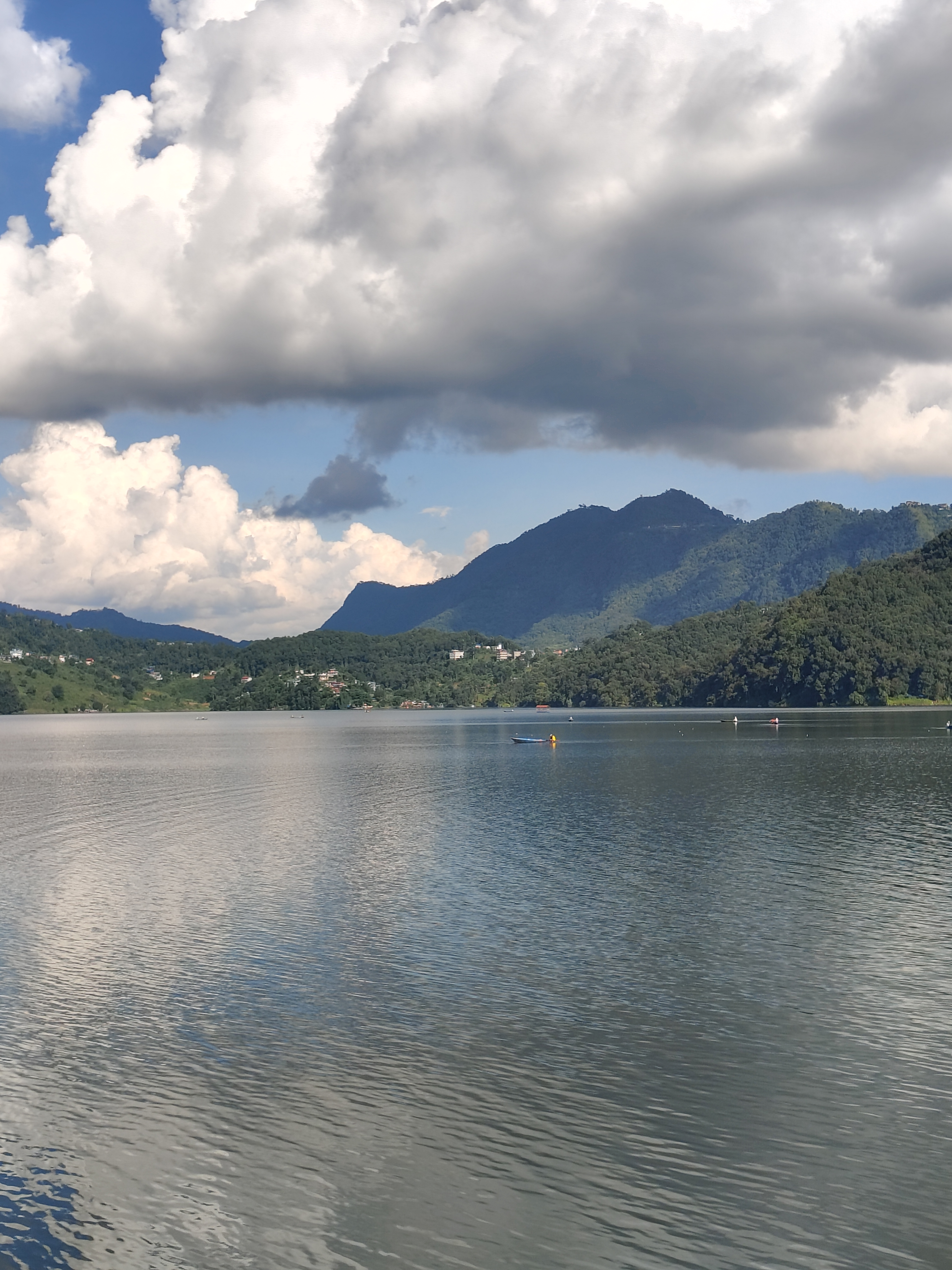 A serene landscape featuring a calm lake surrounded by lush green hills and mountains