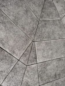 An abstract view of a textured surface composed of angular, geometric tiles in shades of gray.