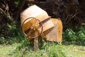 A Yellow concrete mixer in lushy grass
