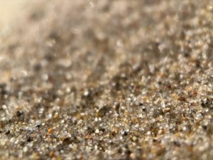 Extreme closeup of beach sand, showing the shapes of individual grains.