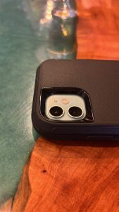 The top of the back of a cell phone, posed so we can see the camera.  It's lying on a bar top made of wood and epoxy.