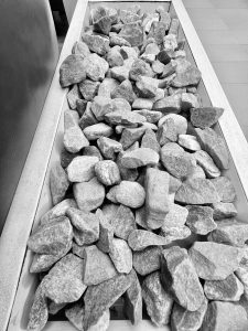 A black and white photo shows a long, narrow planter filled with gray rocks.