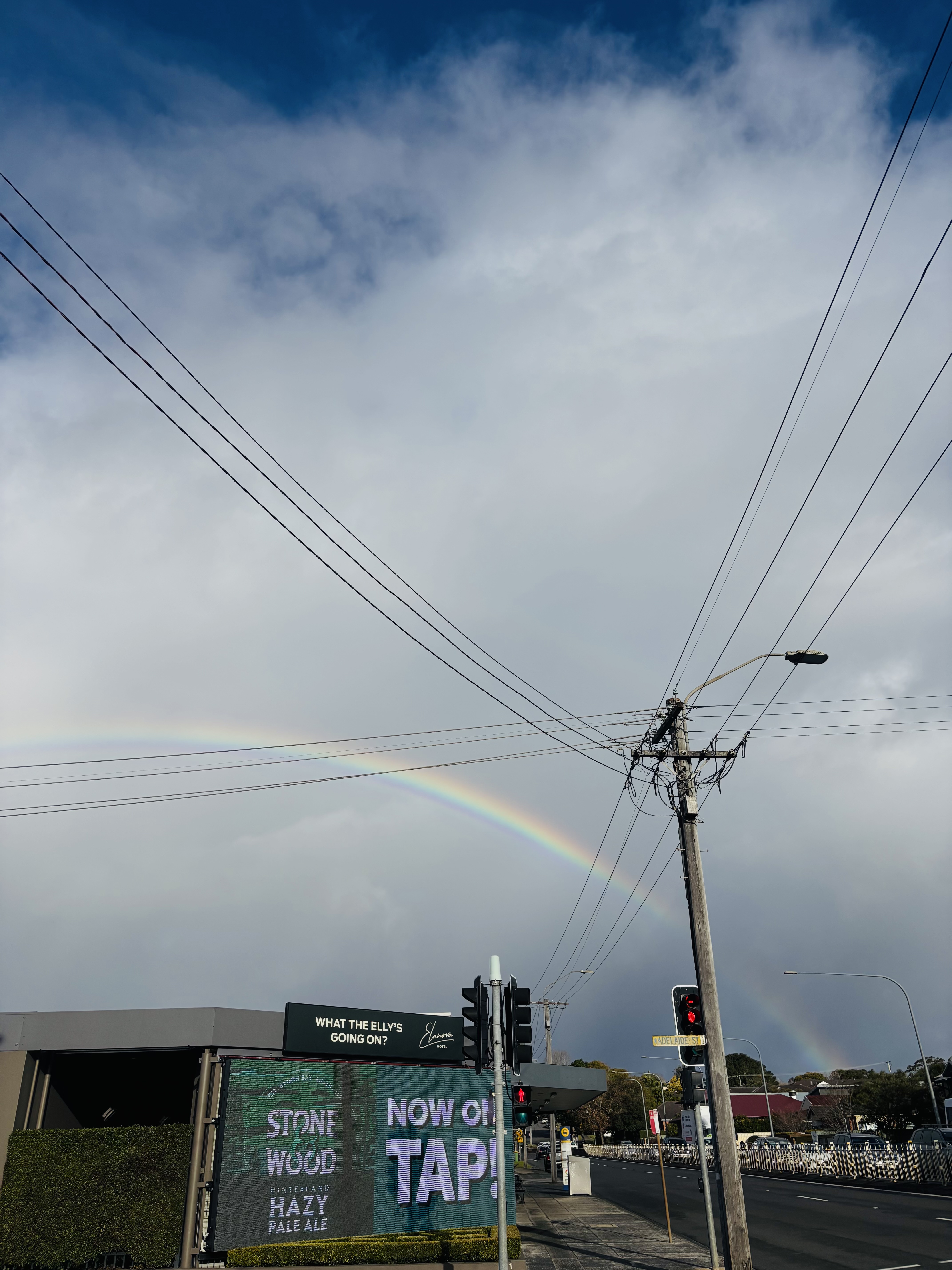 Rainbow in a cloudy sky over a cityscape.