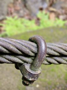 A detailed close-up of an old, rusted metal clamp holding together thick suspension bridge cables. Captured near the hanging bridge at Thusharagiri Falls, Kozhikode. 