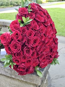 A large heart-shaped bouquet of red roses placed on a stone bench at Pittock Mansion, Portland. Captured in the evening with soft natural light.