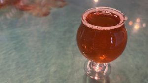 Dark mead in a small tulip glass on a bar top.