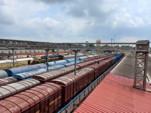 A busy railway yard featuring a long line of freight trains with varying colored cargo containers.