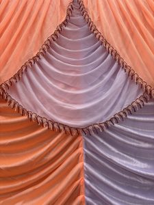 A close-up view of draped fabric in soft hues of orange and light purple.